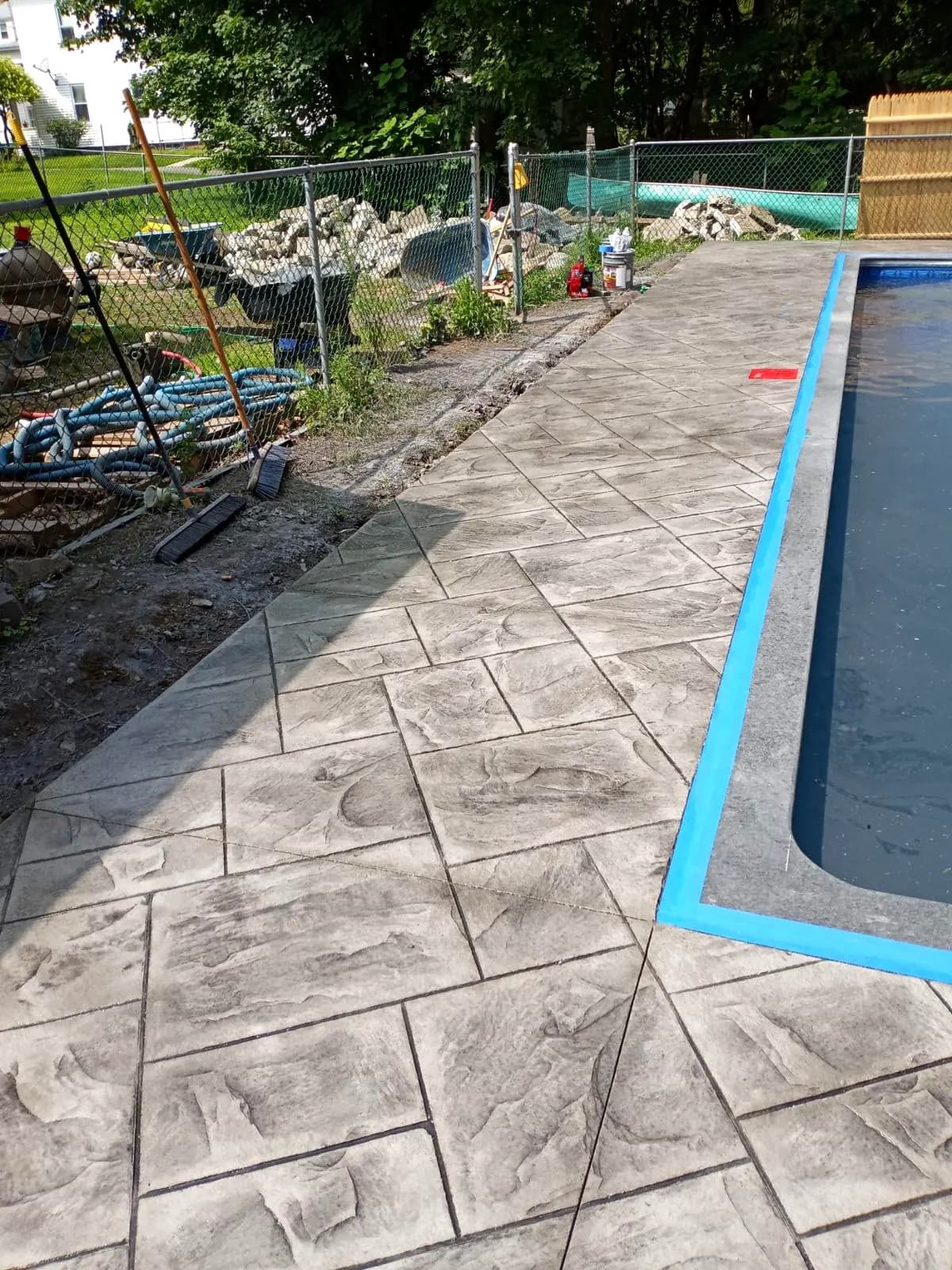 Custom stamped concrete pool deck and patio installation on a wooded Sudbury, MA property