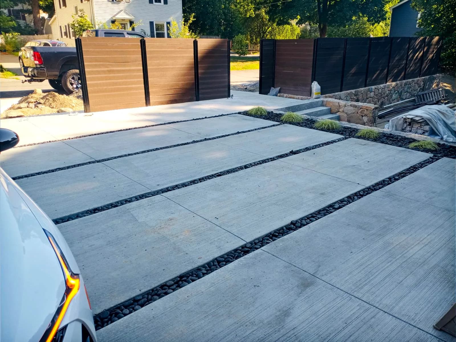 Modern concrete driveway with river rock landscaping strips in a Shrewsbury, Massachusetts neighborhood
