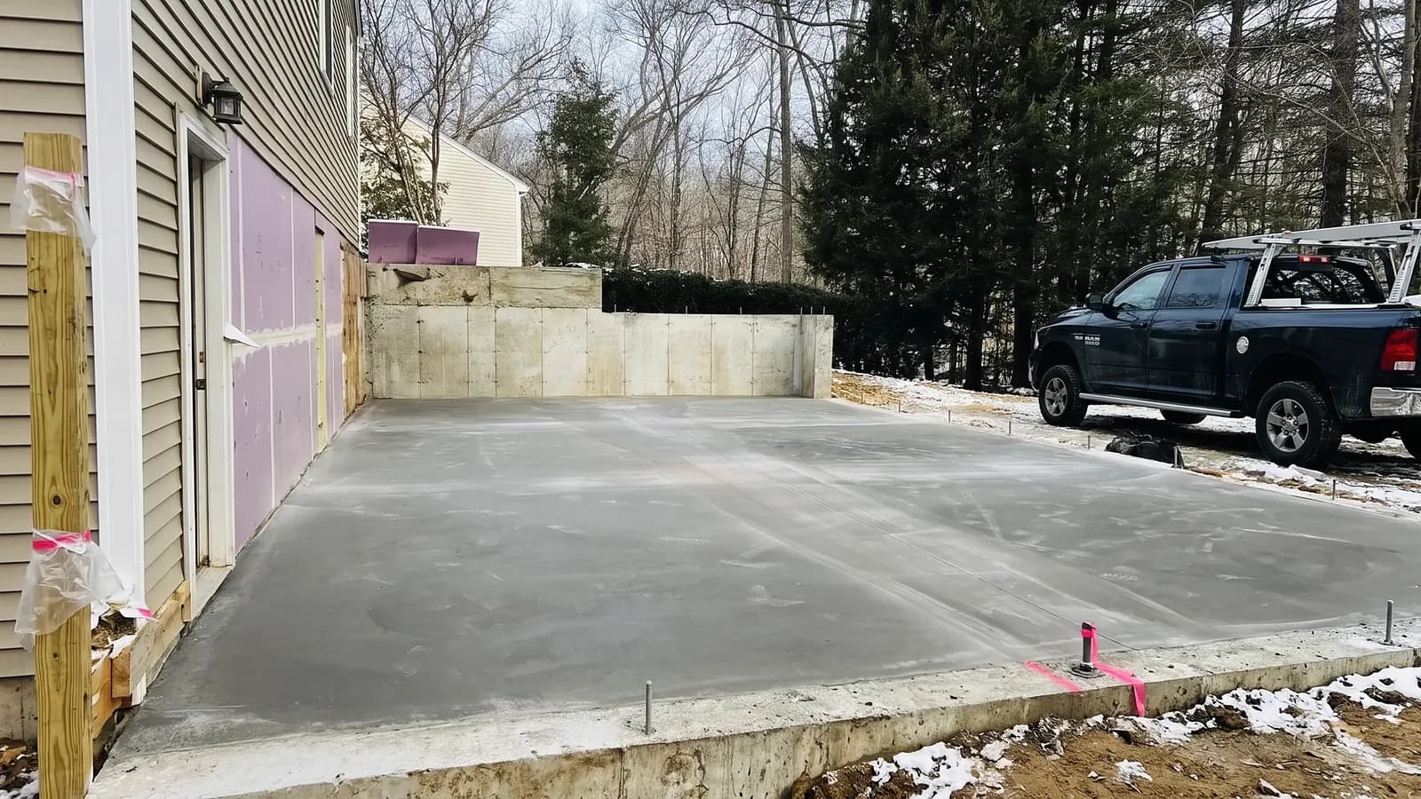 Newly poured concrete foundation slab installation on a sloped residential lot