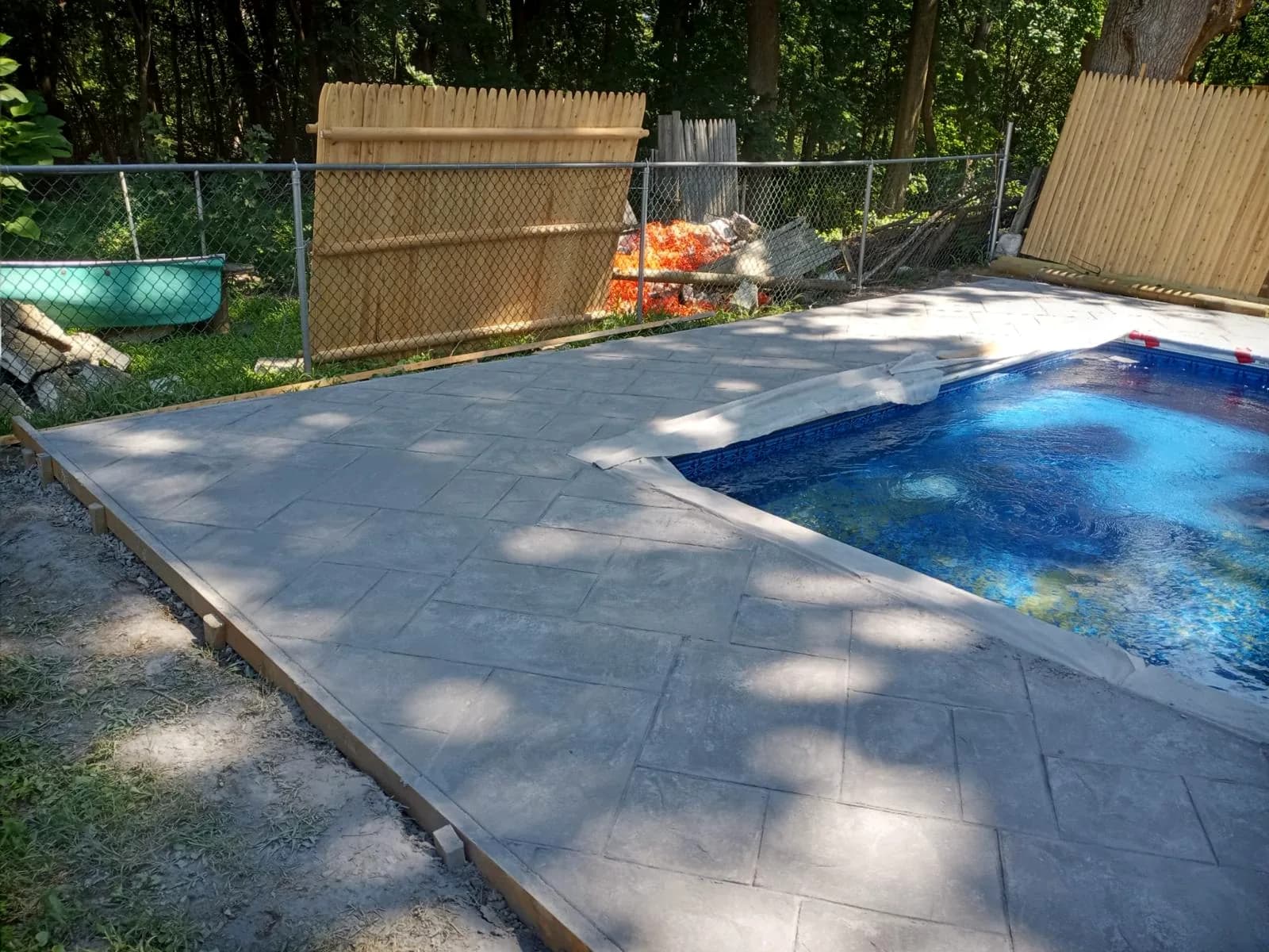Finished stamped concrete pool deck surrounding an in-ground pool in Massachusetts